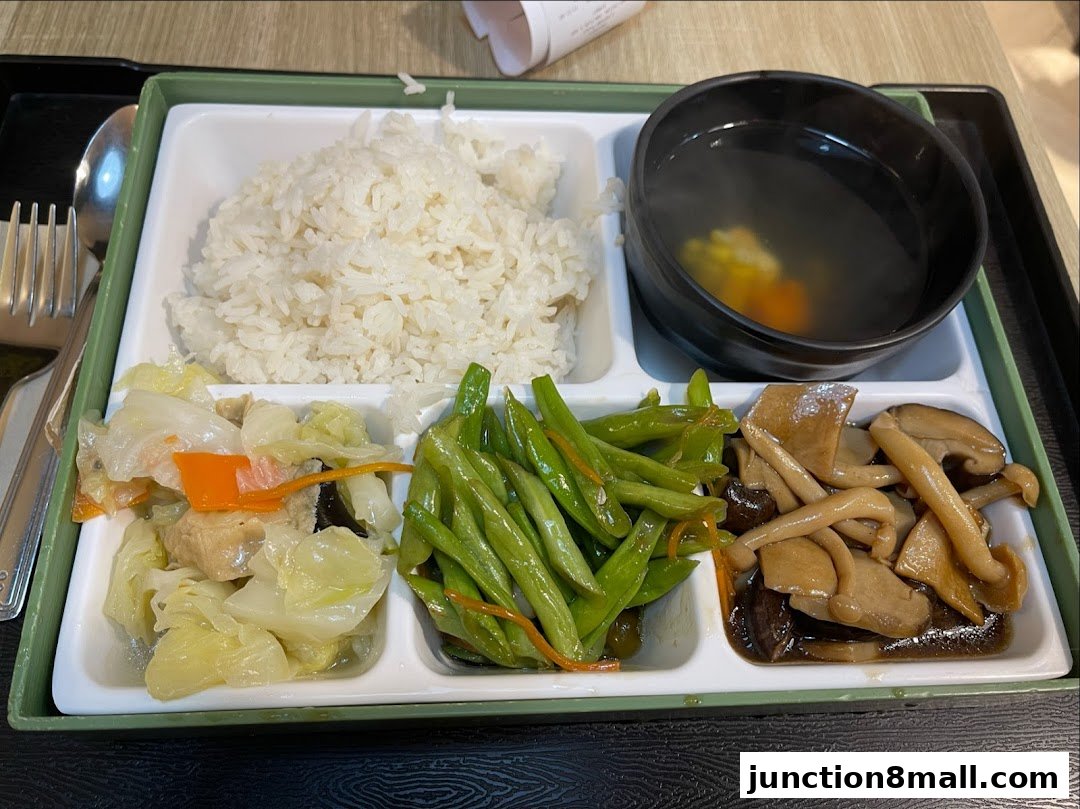 A bento box meal with rice, stir-fried vegetables, mushrooms, and soup.