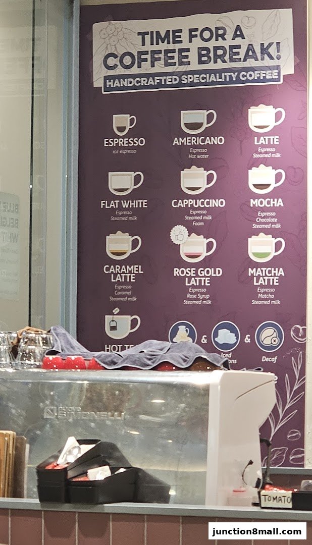 A menu board displays various handcrafted specialty coffees and hot tea.