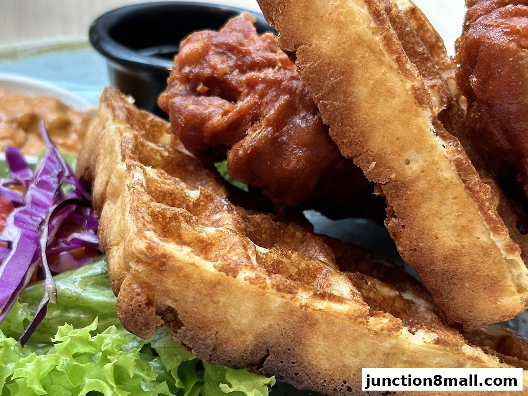 A close-up shot of crispy fried chicken served with golden waffles and a side salad.