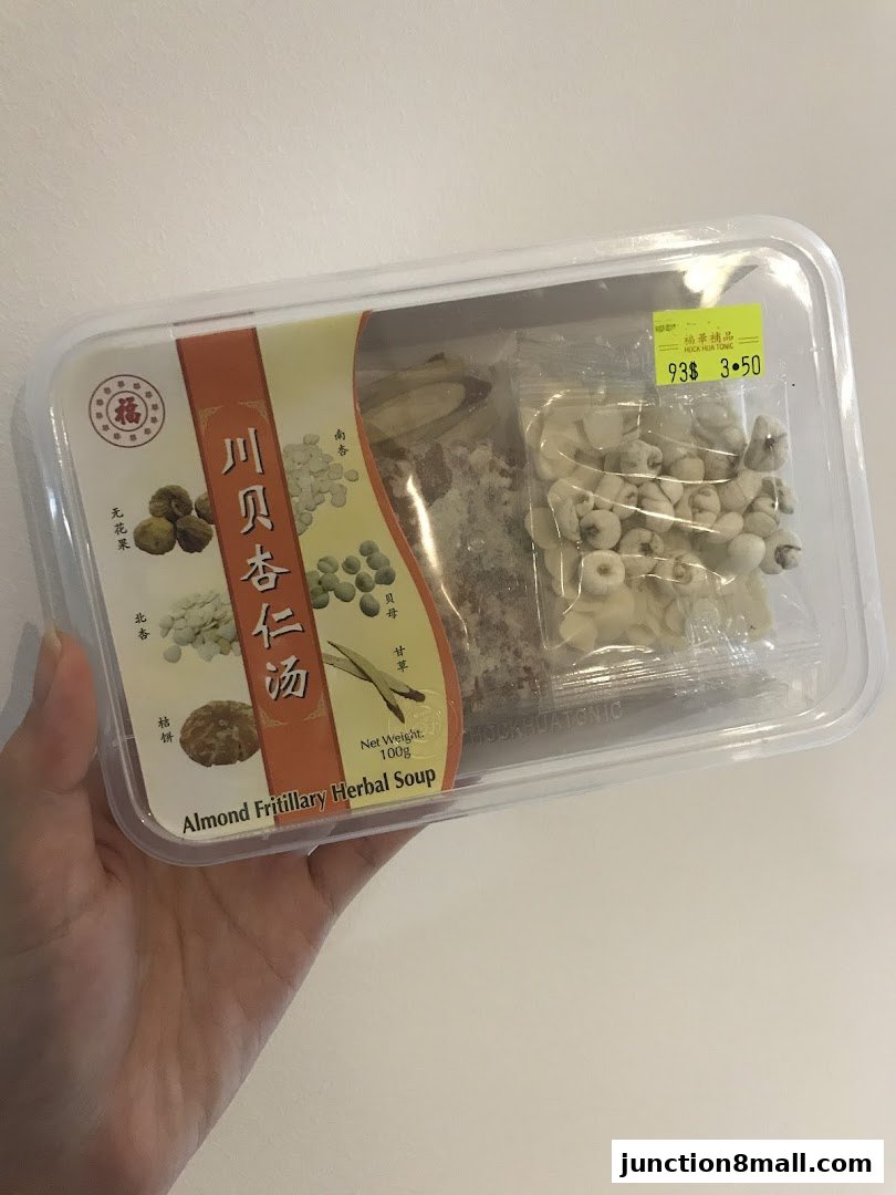 A hand holds a clear plastic container with ingredients for Almond Fritillary Herbal Soup.