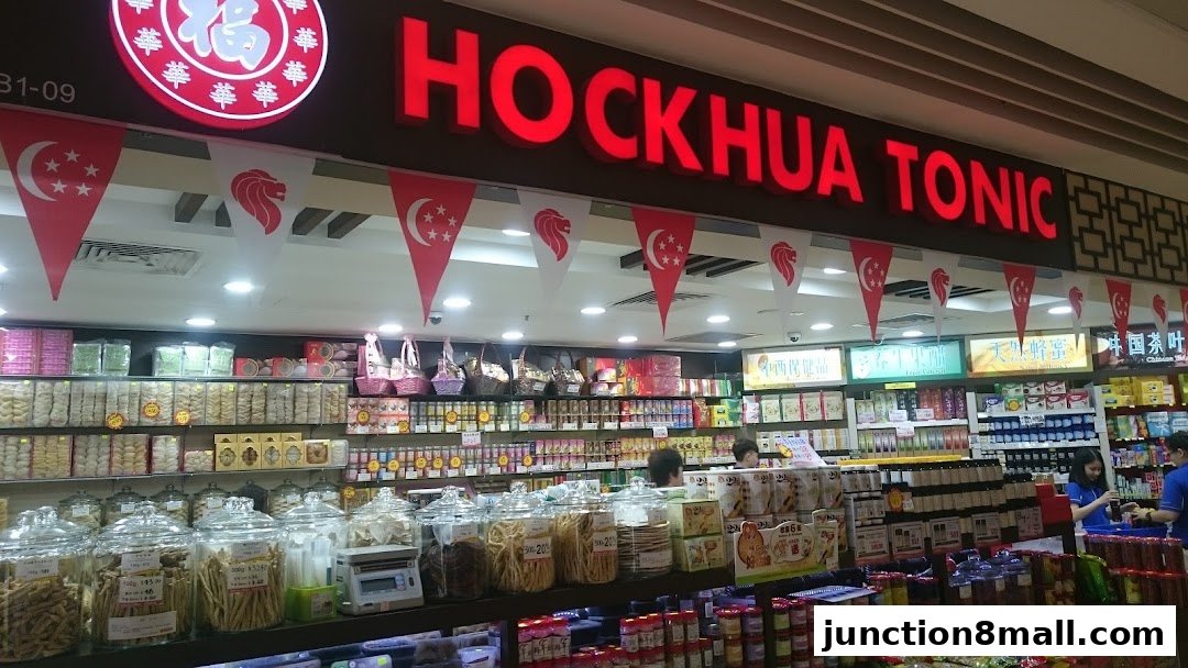 A well-stocked shop with a prominent sign for Hockhua Tonic, featuring various health products and snacks.
