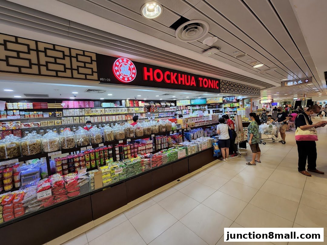 A wide shot of the Hockhua Tonic shop interior, showcasing shelves stocked with various health products and customers browsing.