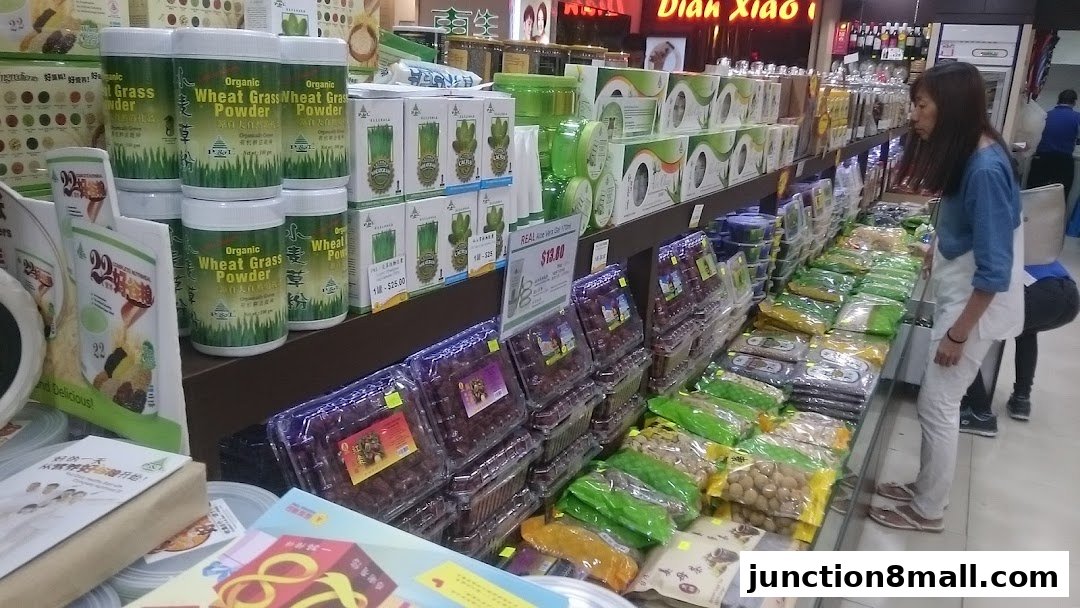 A woman browses a well-stocked aisle of health products, including wheat grass powder and dried fruits.
