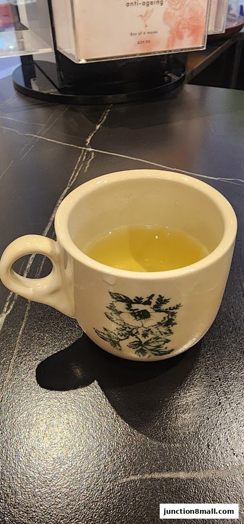 A close-up of a vintage-style mug filled with a light-colored liquid, placed on a dark, textured surface.