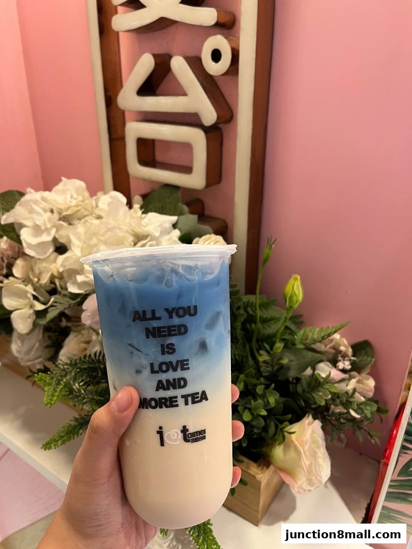 A hand holds a layered bubble tea with a motivational quote on the cup.