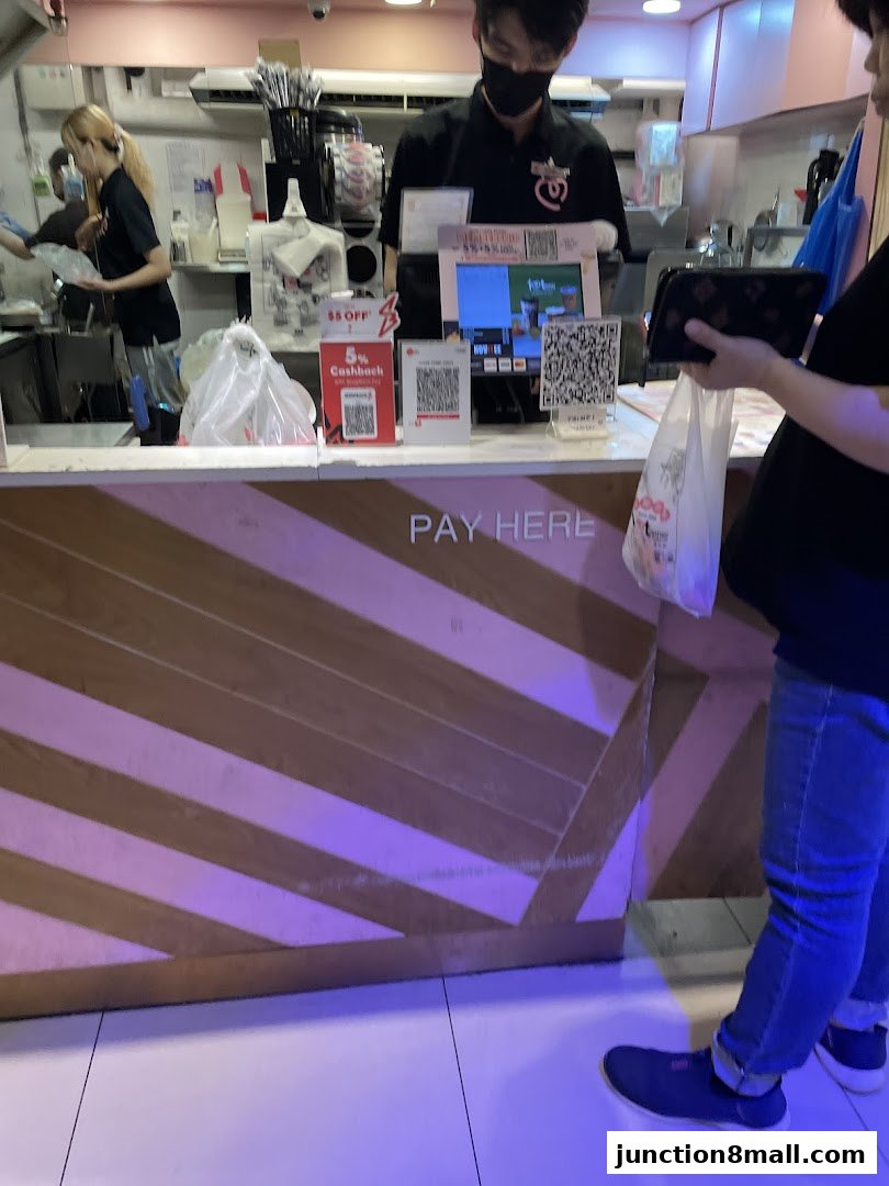 Customers paying at the counter of a fried chicken and bubble tea shop.