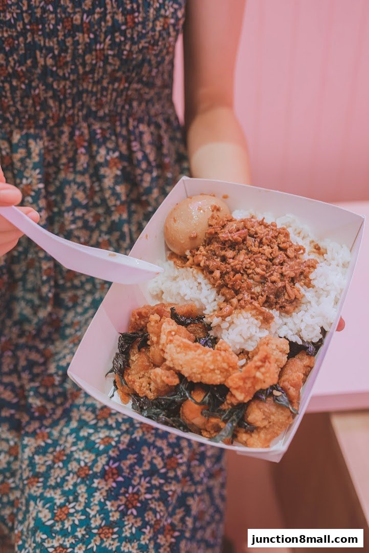 A person holds a takeout container filled with Taiwanese fried chicken, rice, and braised egg.