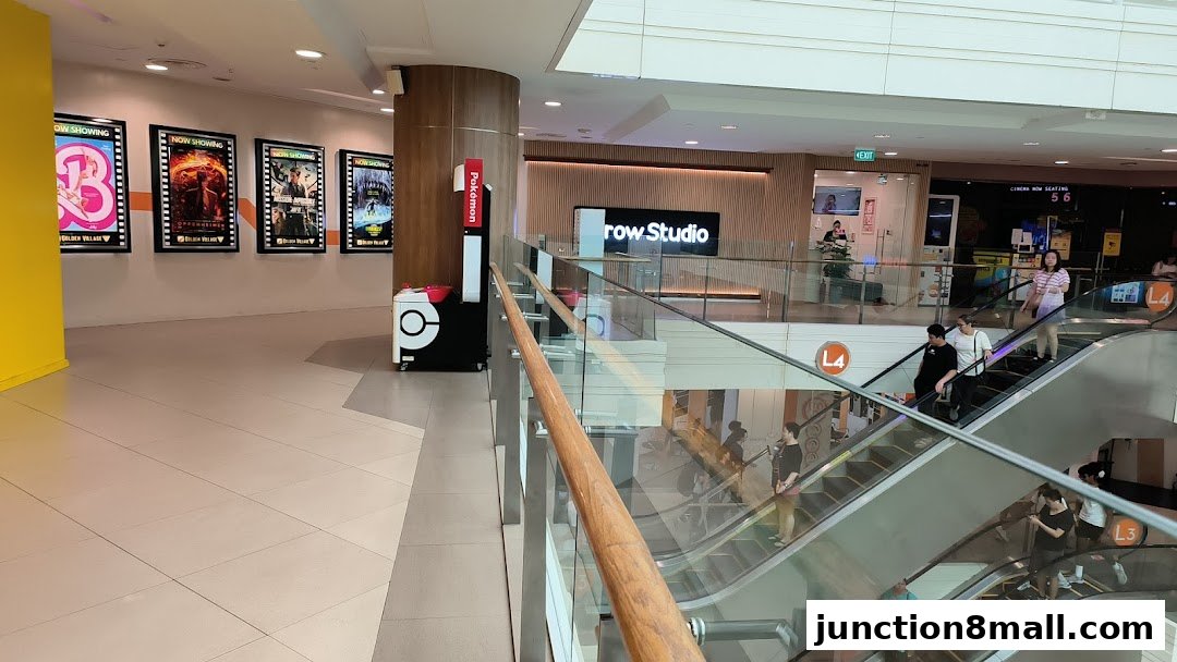 Interior view of a shopping mall with escalators, movie posters, and the iBrow Studio shop.