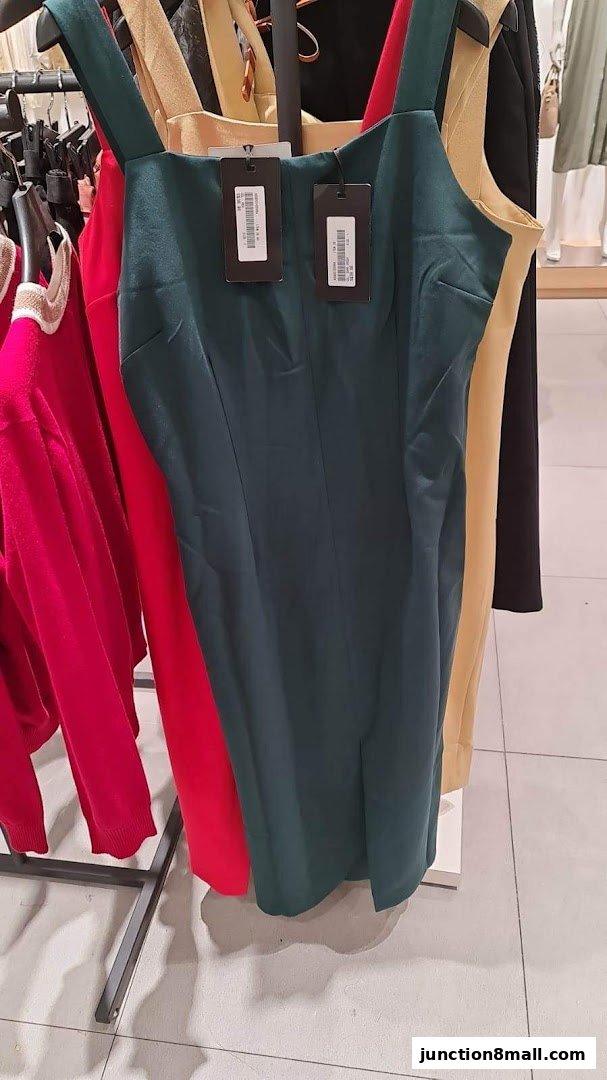 A close-up of dresses on hangers, featuring a dark green dress with tags.
