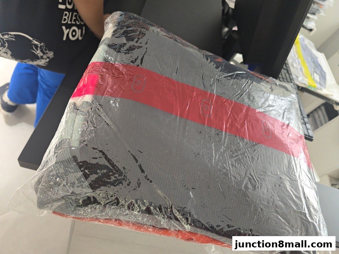 A folded item wrapped in plastic with a red stripe and visible text.