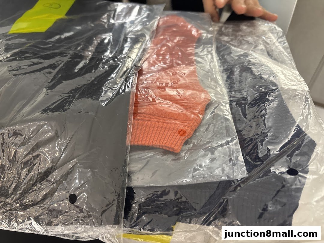 Close-up of neatly packaged clothing items, including a black top and an orange sweater.