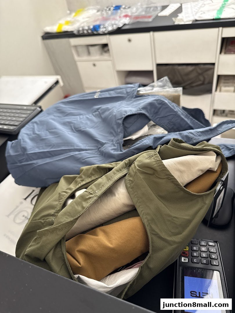 Folded clothing items in a retail store, with a payment terminal and keyboard visible.