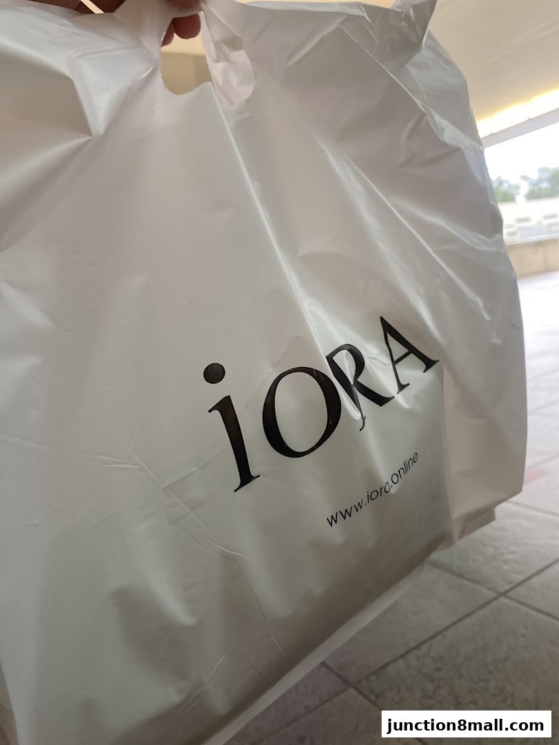A white shopping bag with the iORA logo and website printed on it.