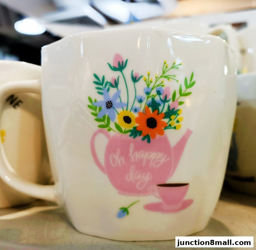 A white mug with a pink teapot and floral design, saying 'oh happy day'.
