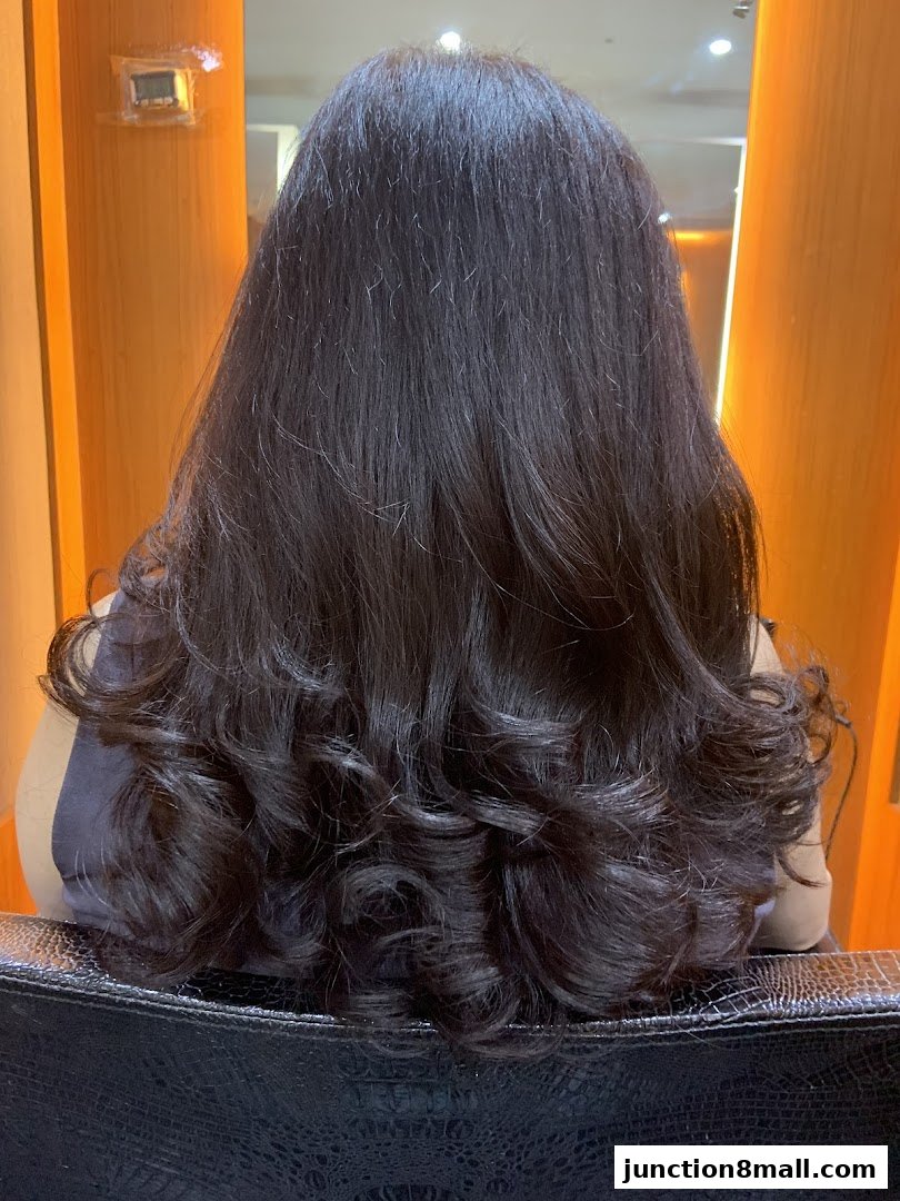 A person's back with long, dark, styled hair with curls.