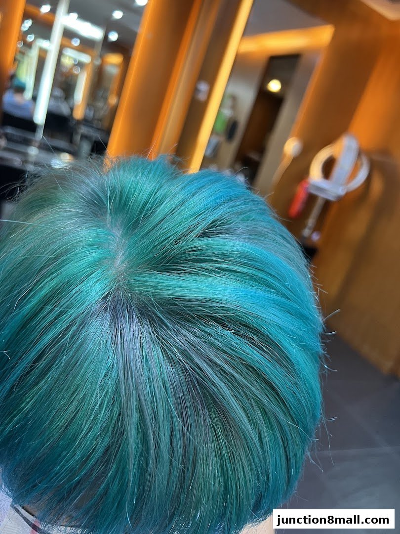 Close-up of a person's head with vibrant teal and green dyed hair.