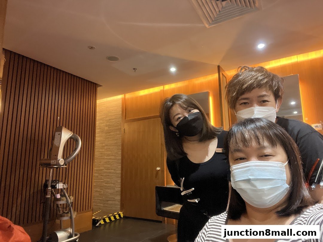 Three people wearing masks pose for a selfie inside a modern salon.