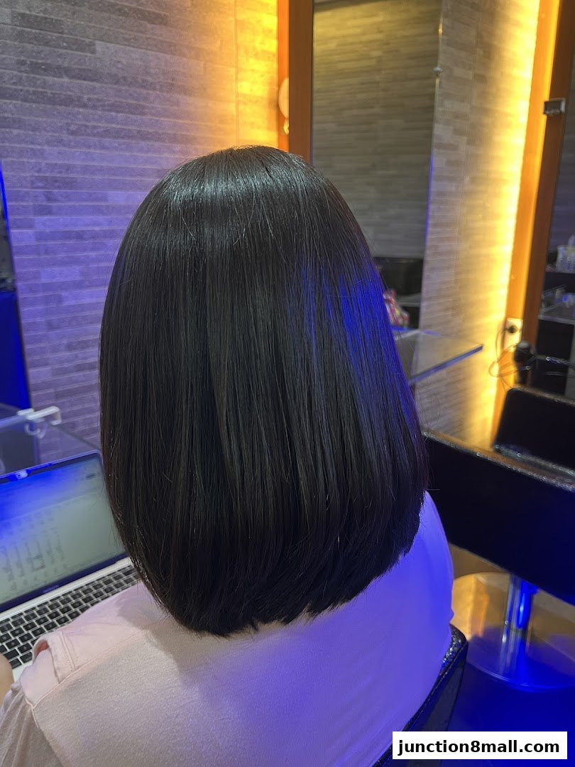 A person with freshly styled, dark, bob-cut hair sits in a salon chair.