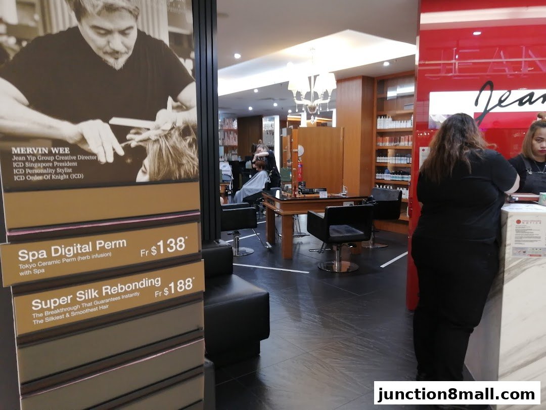 Interior of a Jean Yip Hairdressing salon with staff and service price displays.