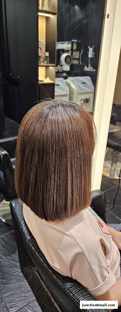 A person with a fresh bob haircut sits in a salon chair, showcasing a stylish new look.