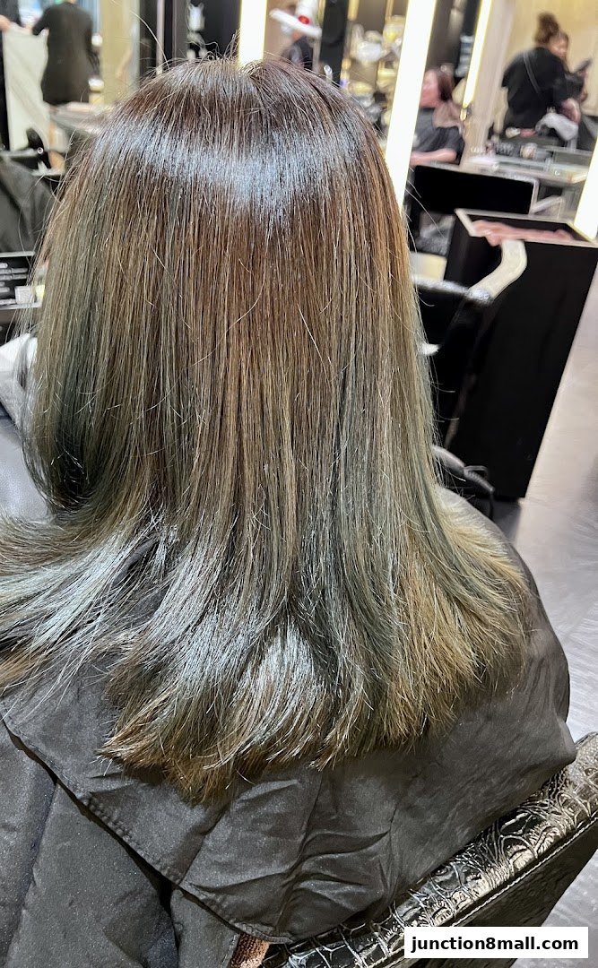A person's back with stylishly colored hair in a salon setting.