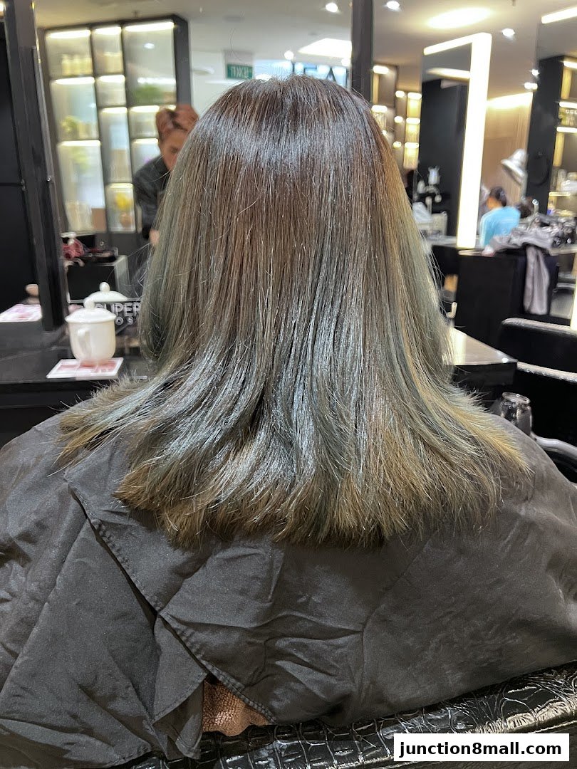 A person's back with newly colored hair in a salon setting.