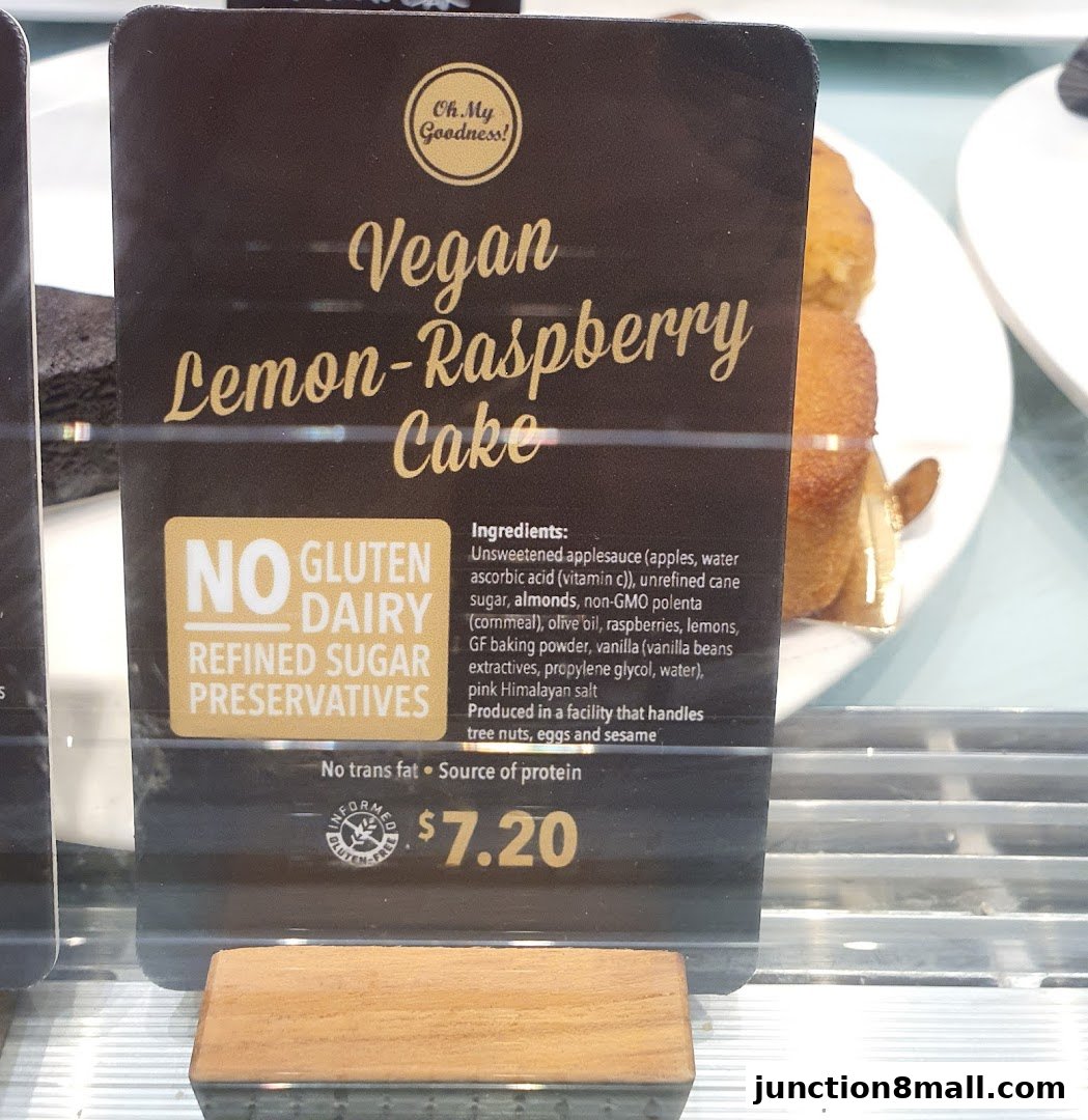 A sign displays a Vegan Lemon-Raspberry Cake with its ingredients and price.