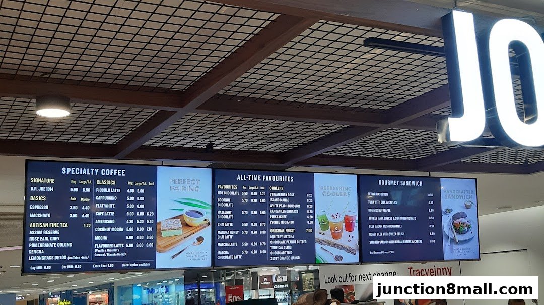 A digital menu board displaying specialty coffees, all-time favorites, and gourmet sandwiches at Joe Dough.