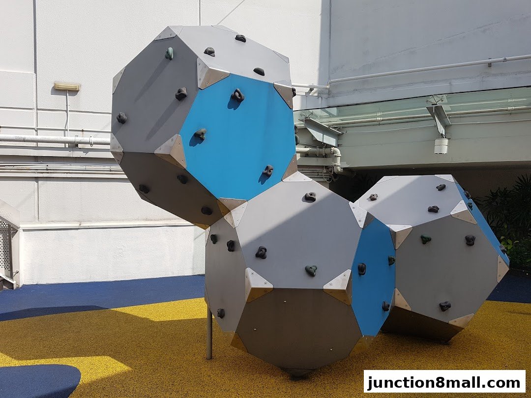 A unique geometric climbing structure with blue and gray panels and climbing holds.