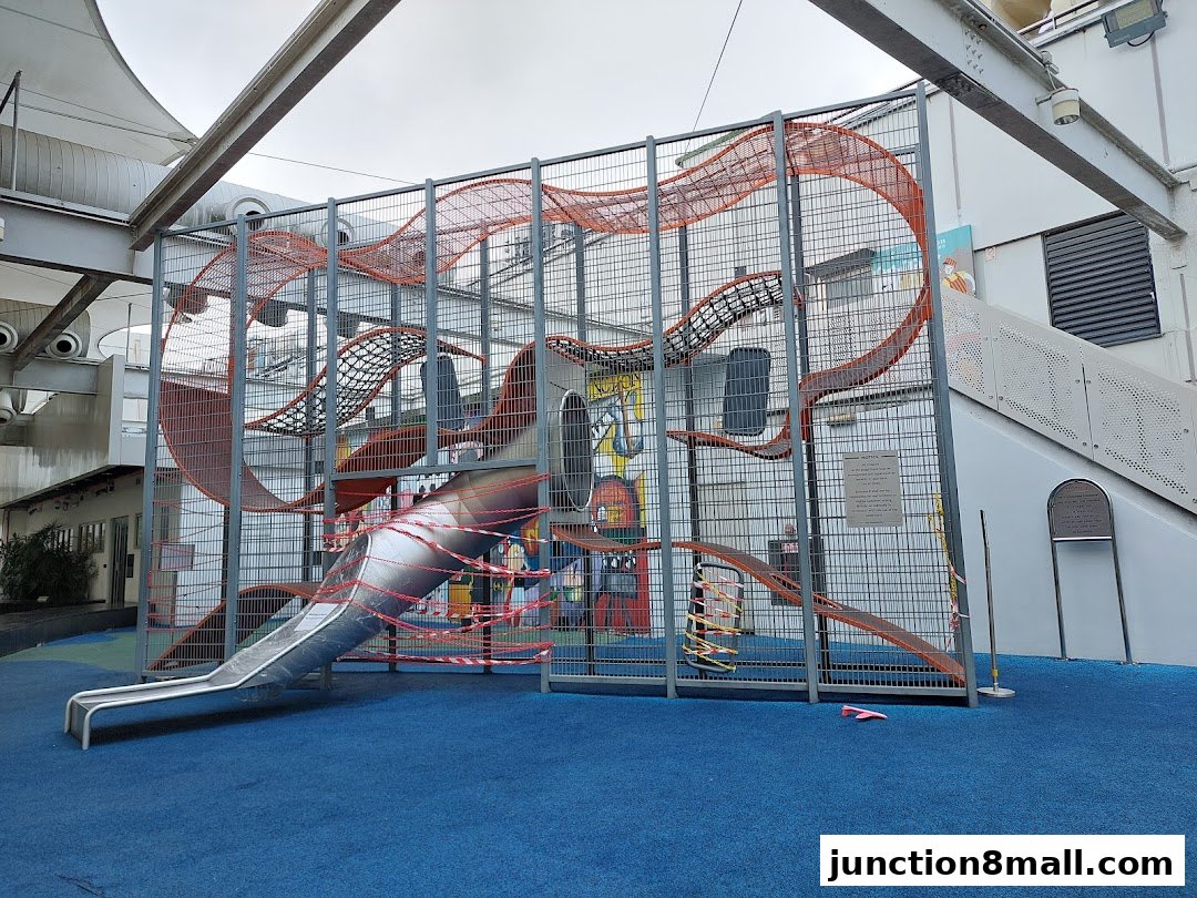 A large, enclosed playground structure with slides and climbing nets, cordoned off with caution tape.