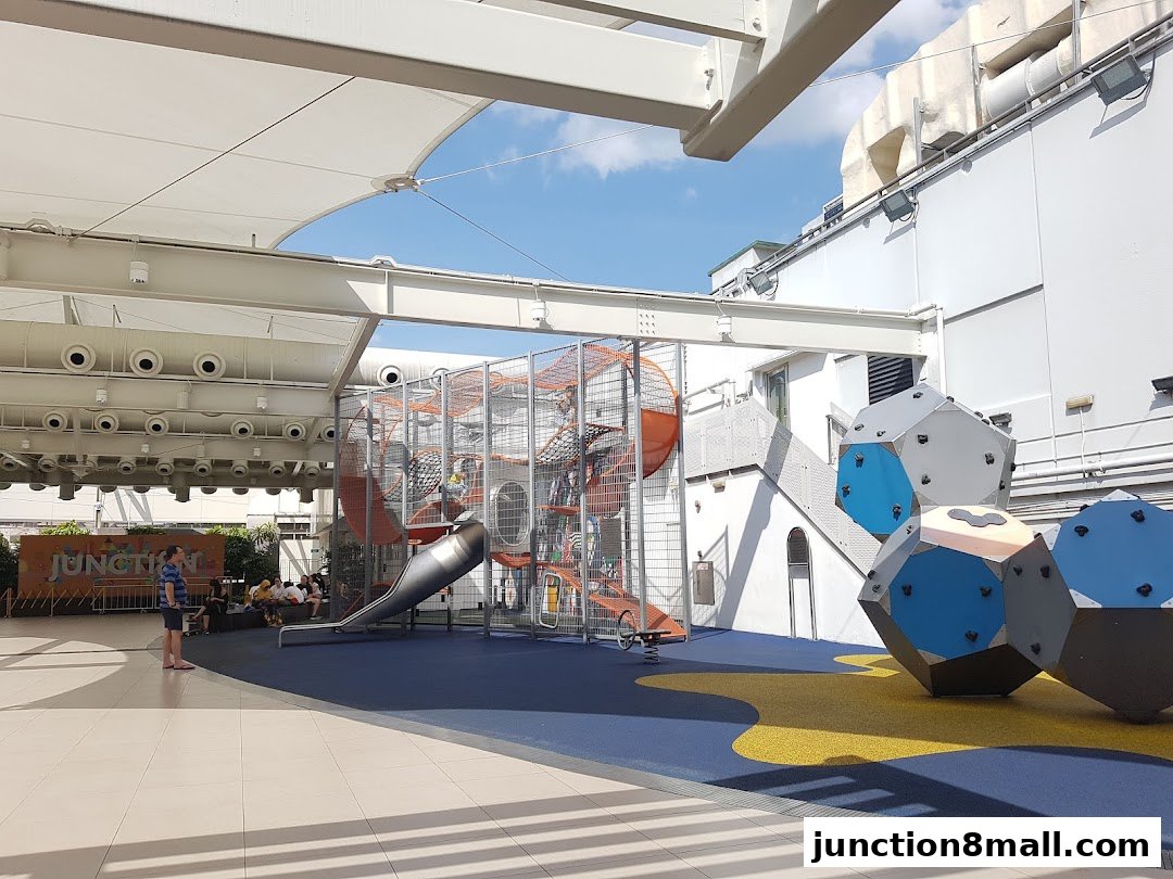 A spacious outdoor playground with climbing structures and a slide under a canopy.