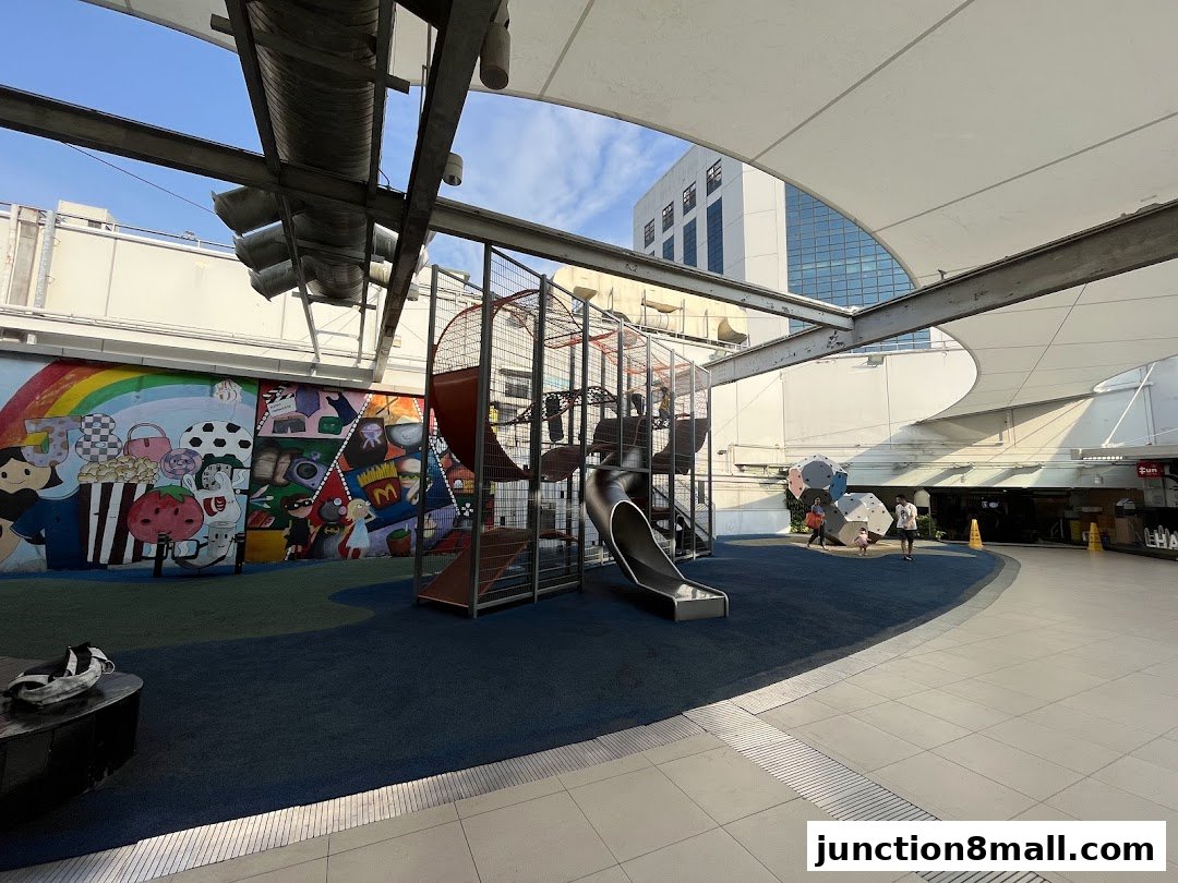 A colorful playground with a climbing structure and slide, featuring a vibrant mural.