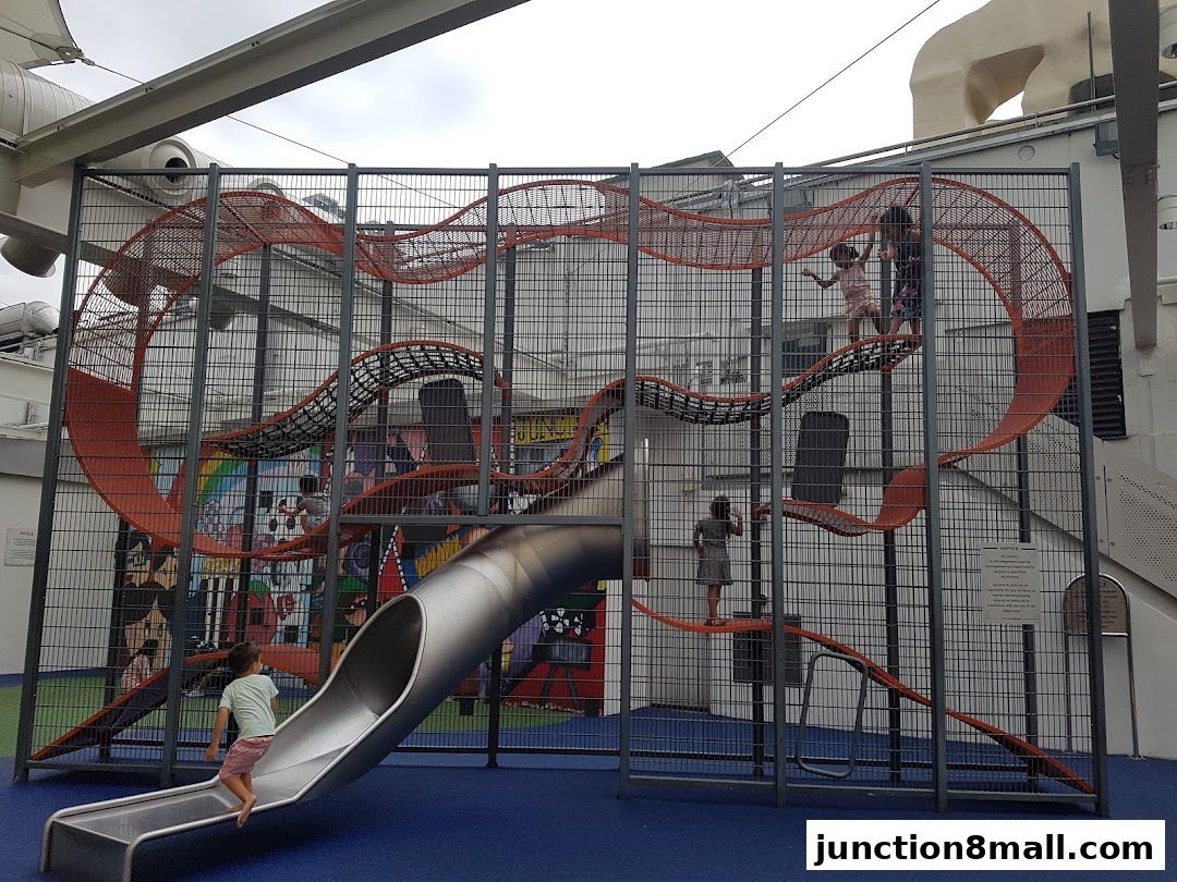 Children playing on a large, multi-level indoor playground with slides and climbing nets.