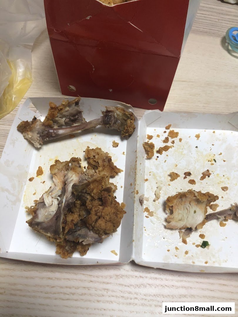 Remains of fried chicken in KFC packaging, showing bones and leftover pieces.