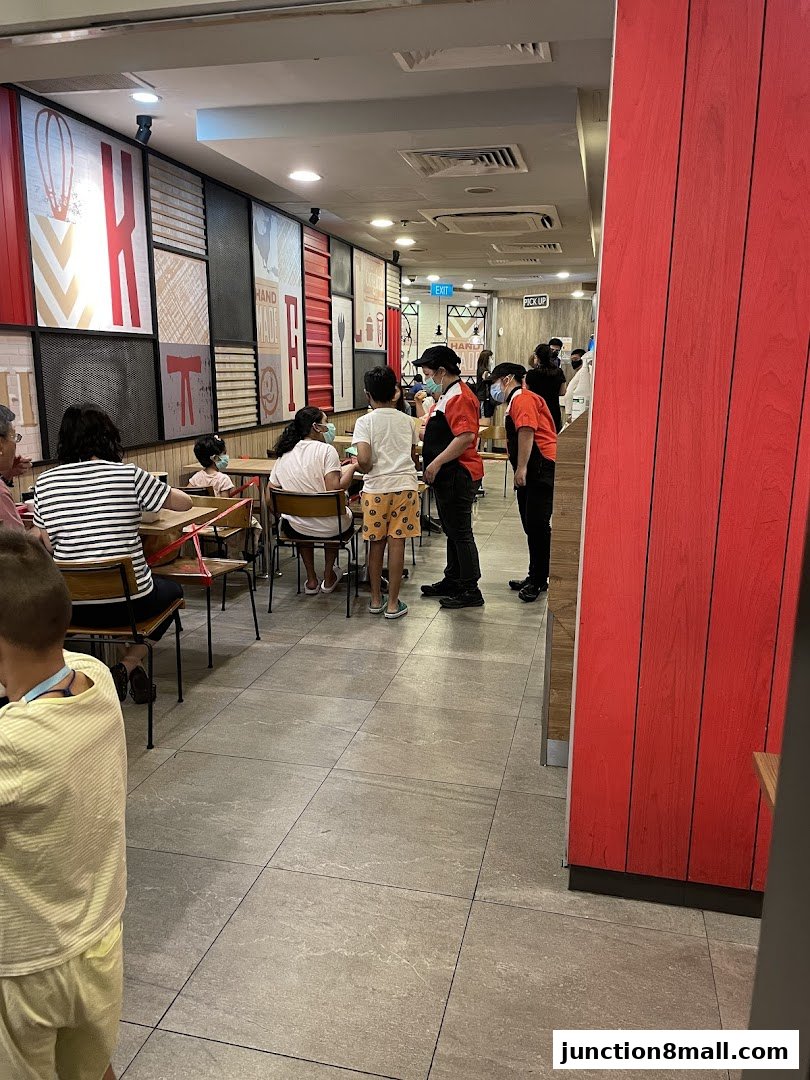 People dining and staff working inside a KFC restaurant with distinctive red and white decor.