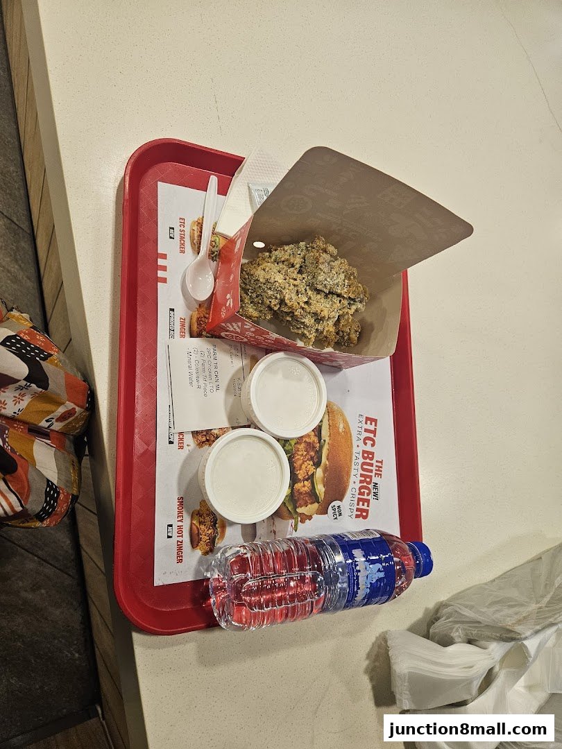 A tray of KFC food including fried chicken, a burger, dipping sauces, and a bottle of water.