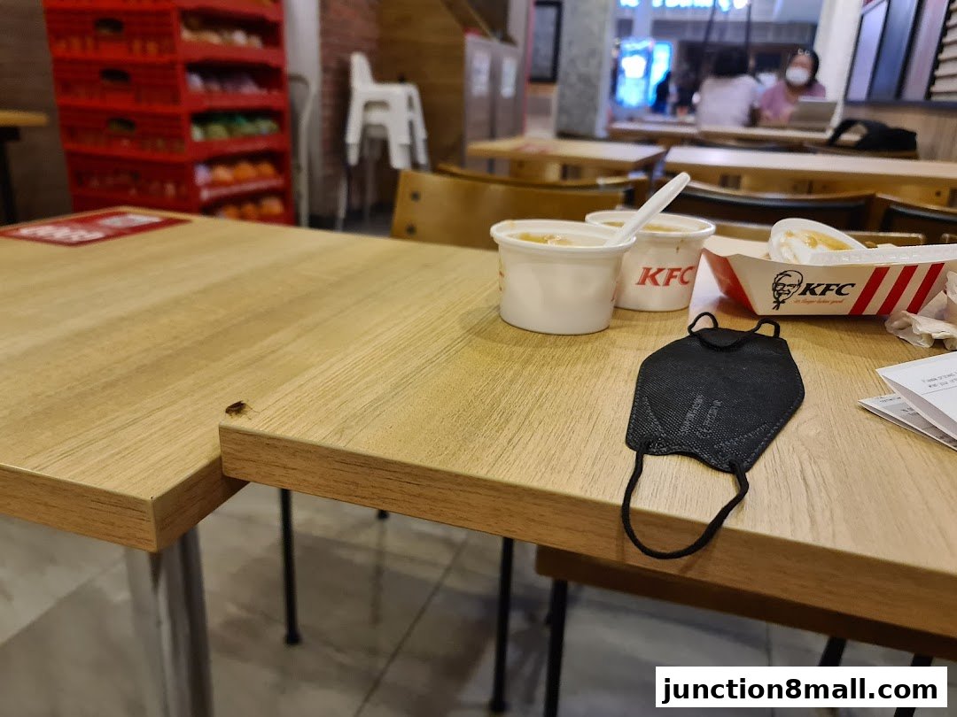 A table at KFC with food, drinks, and a face mask, with a cockroach on the table.