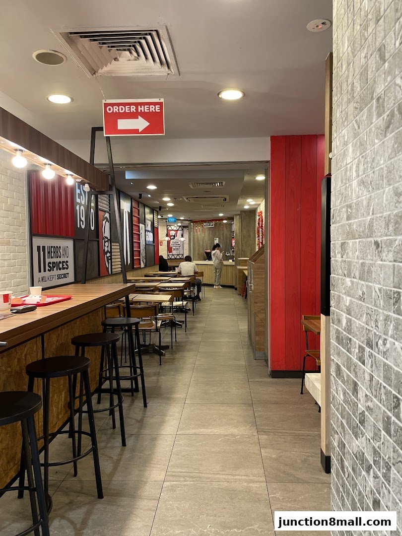 Interior view of a KFC restaurant showing seating, counter, and an 'Order Here' sign.