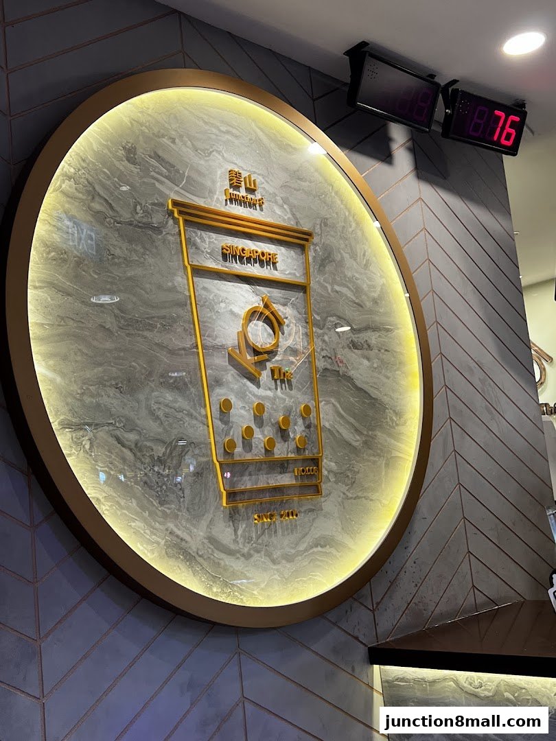 A stylish circular sign for KOI Thé featuring a golden bubble tea cup design.