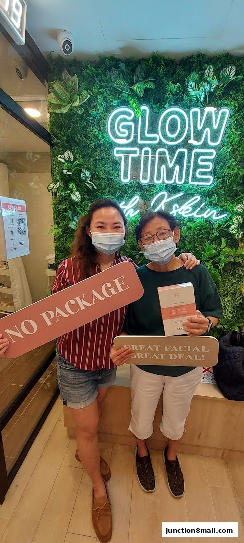 Two women pose with signs promoting Kskin Korean Express Facial services and products.