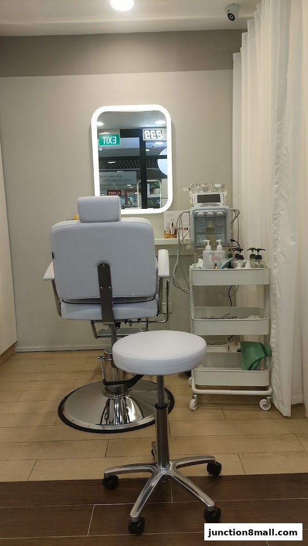 A clean and modern facial treatment room with a chair, stool, and equipment.