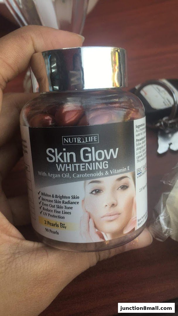 A hand holds a bottle of Nutrilife Skin Glow Whitening supplement with Argan Oil, Carotenoids & Vitamin E.