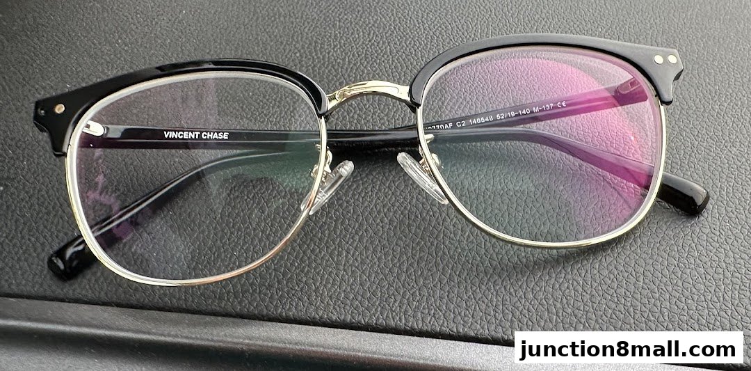 A close-up shot of black and gold framed eyeglasses with clear lenses.
