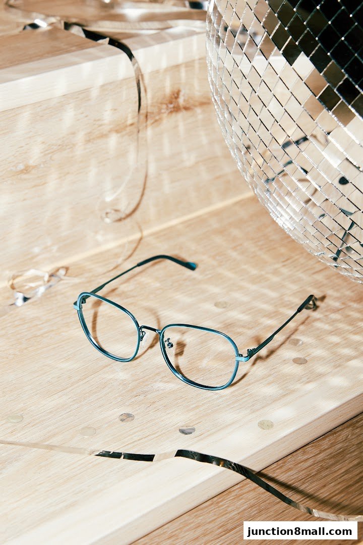 Stylish blue-rimmed eyeglasses are displayed on a wooden surface with a disco ball and confetti.