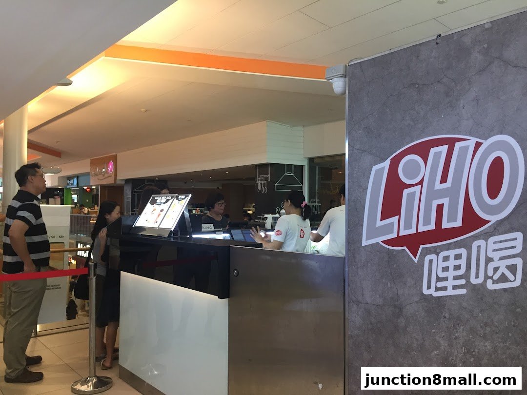 Customers queue at a LiHO TEA counter with staff serving drinks.