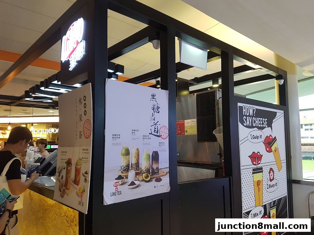 A LiHO TEA shop counter with promotional posters and customers ordering drinks.