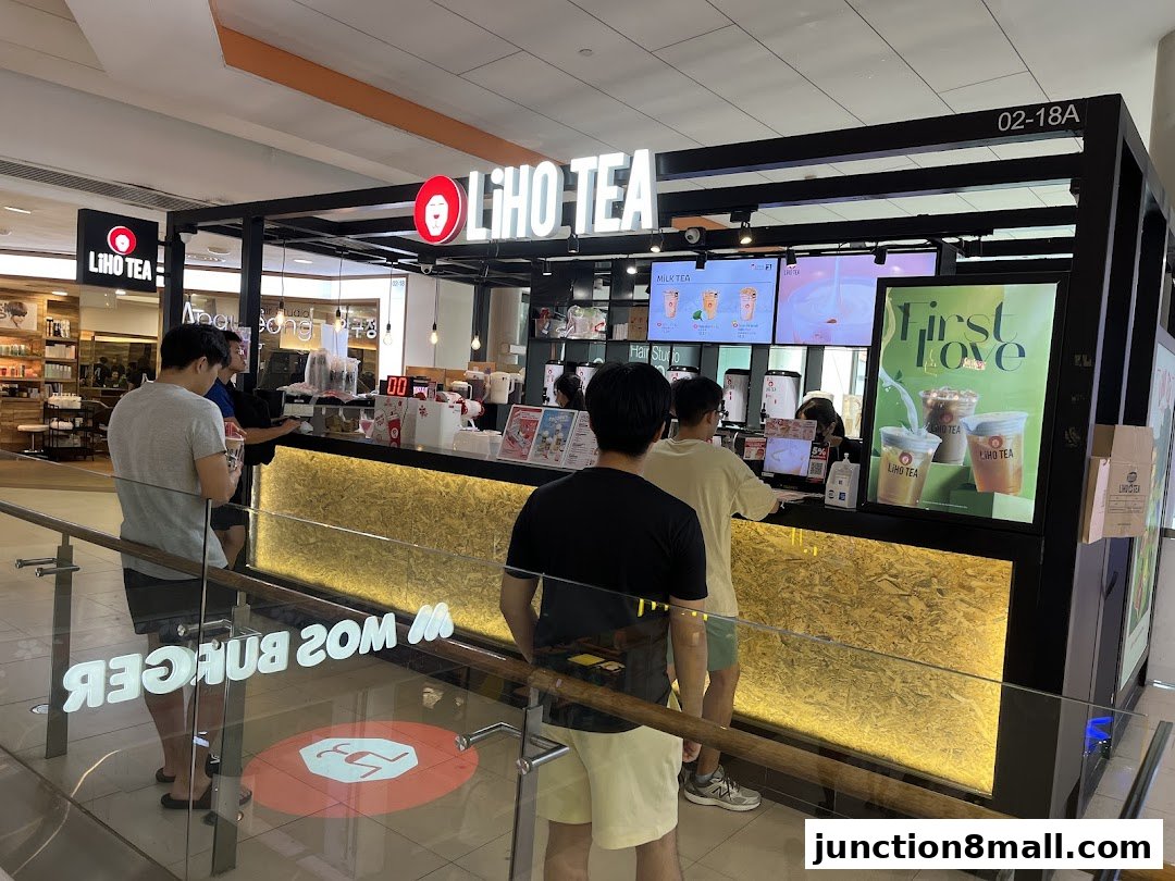 Customers queue at a LiHO TEA shop with illuminated signage and promotional displays.
