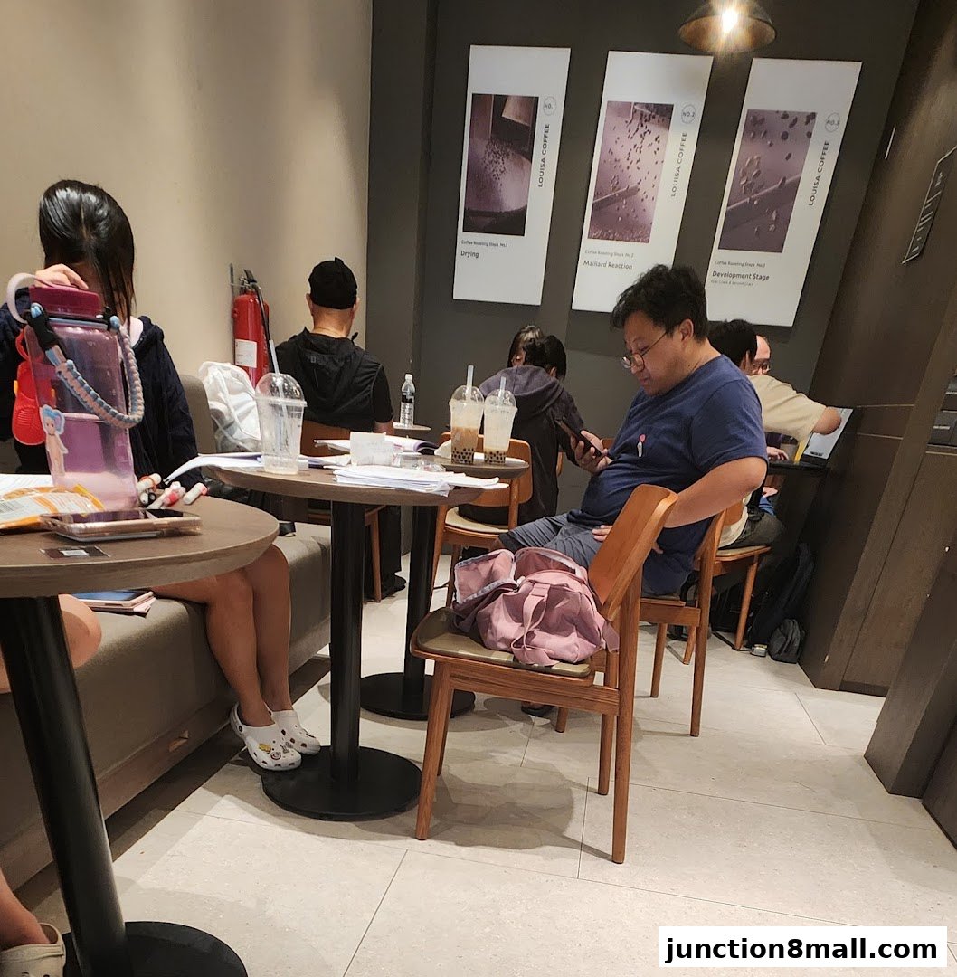 People sitting at tables in a coffee shop, with drinks and papers on the tables.