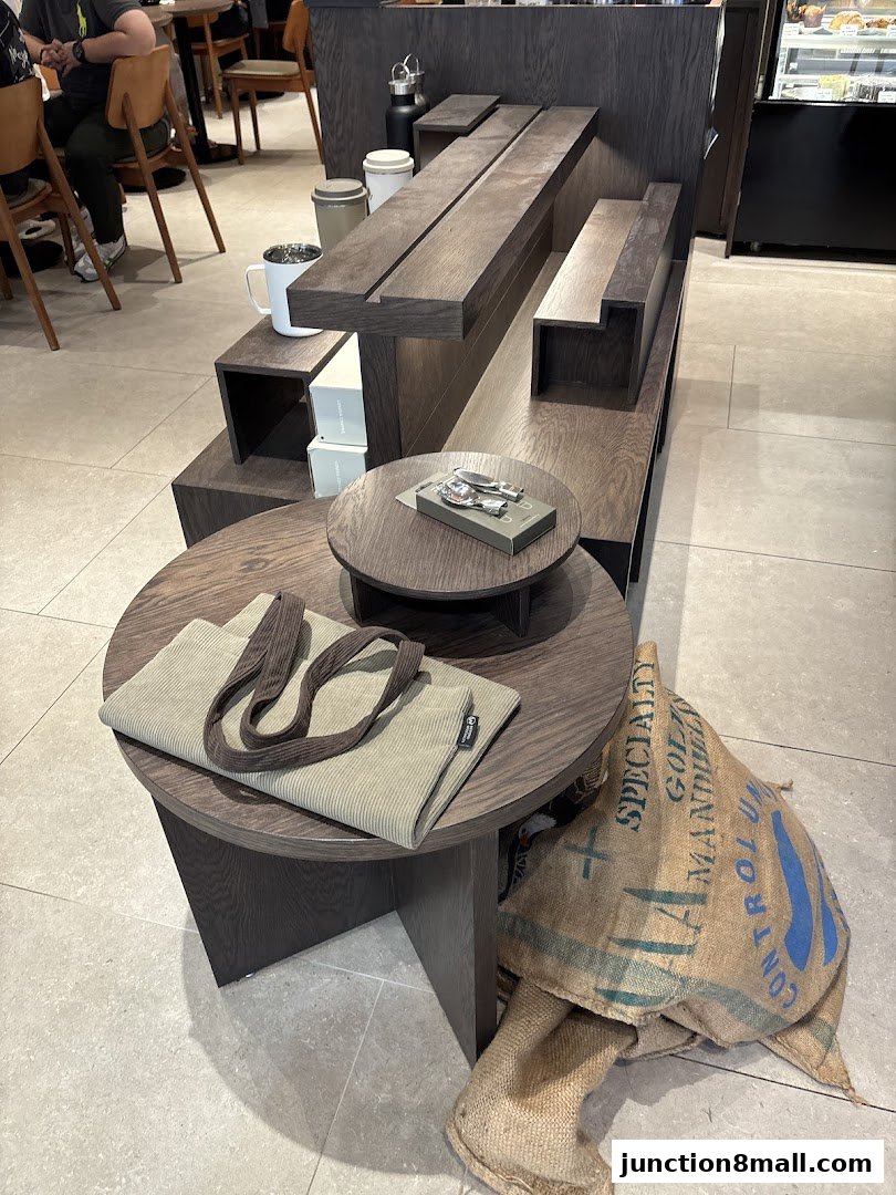 A display of coffee-related items including a tote bag, coffee beans in a burlap sack, and mugs.