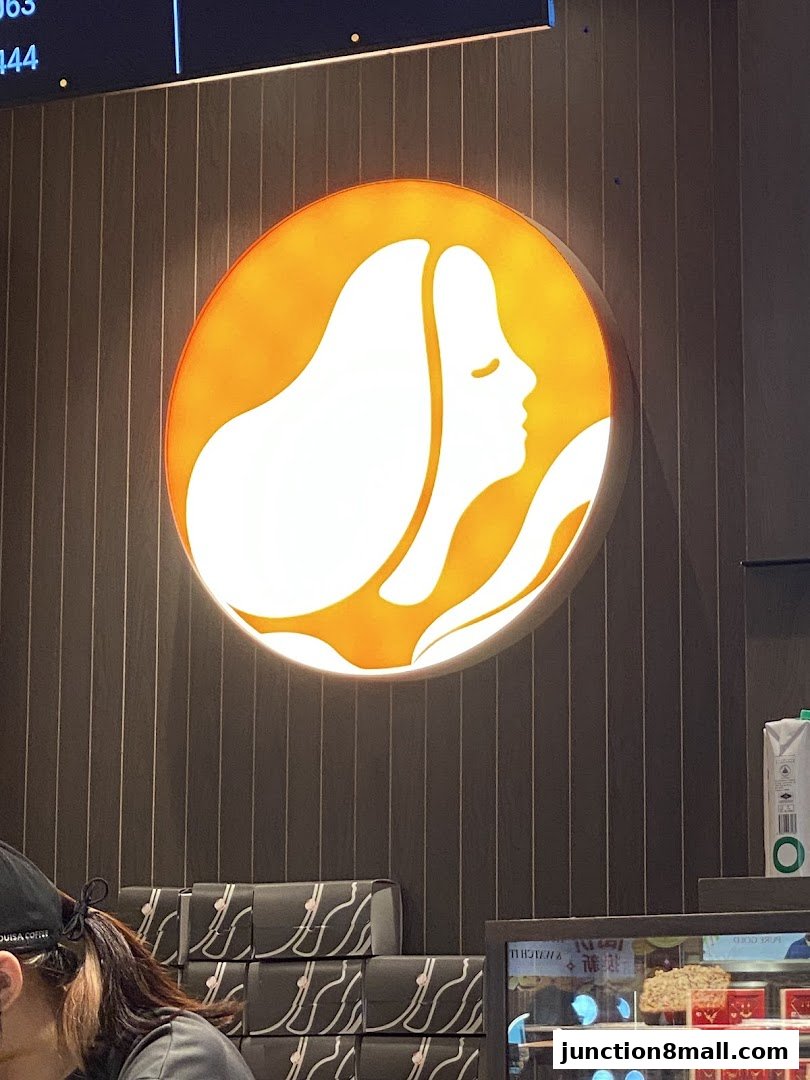 Louisa Coffee shop interior with a prominent illuminated logo and display cases.